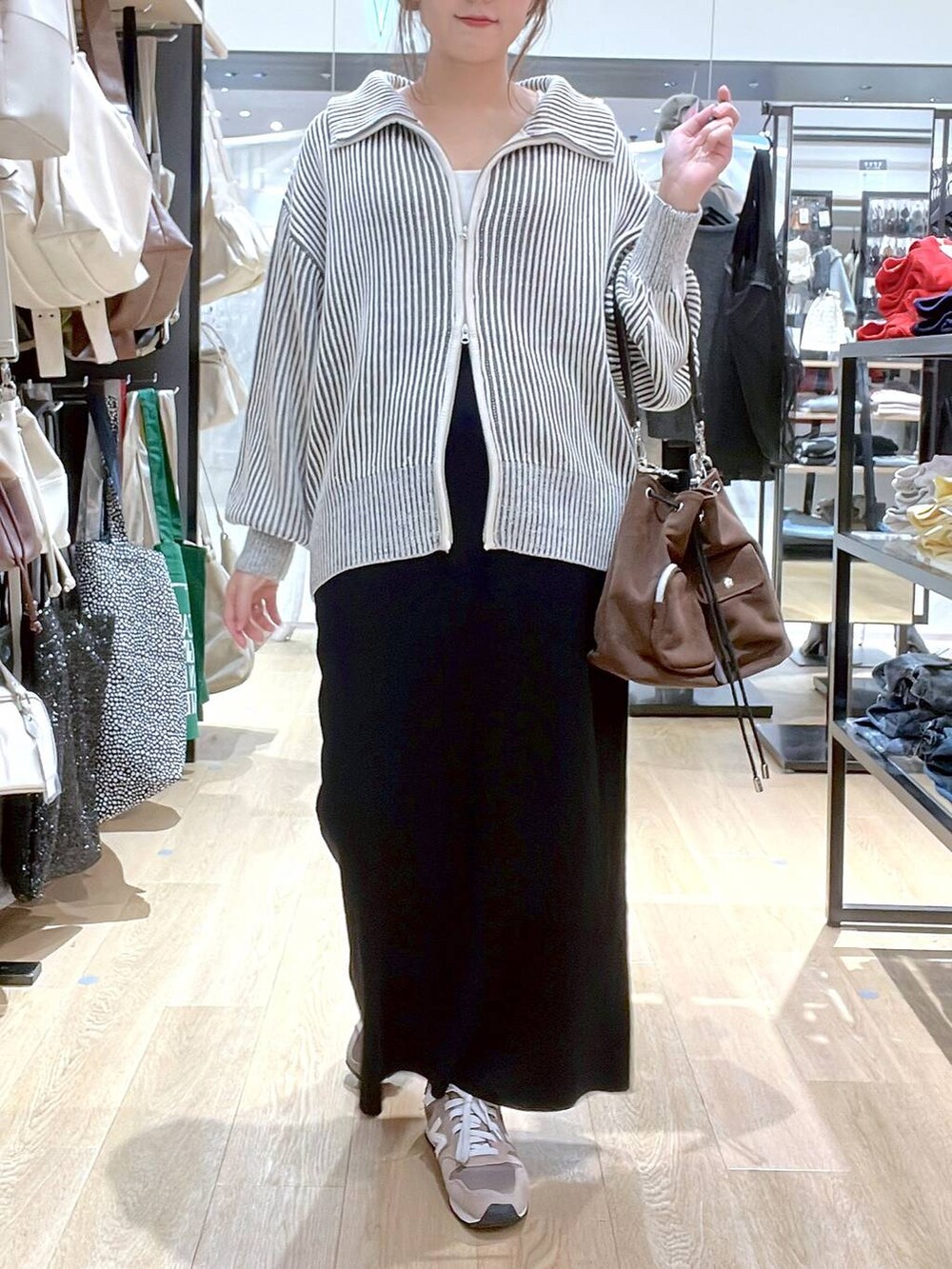 ブラウン系のスニーカー、ブラウン系のショルダーバッグ、ベージュ系のニット/セーターを着用したレディースの秋コーディネートの4枚目の写真