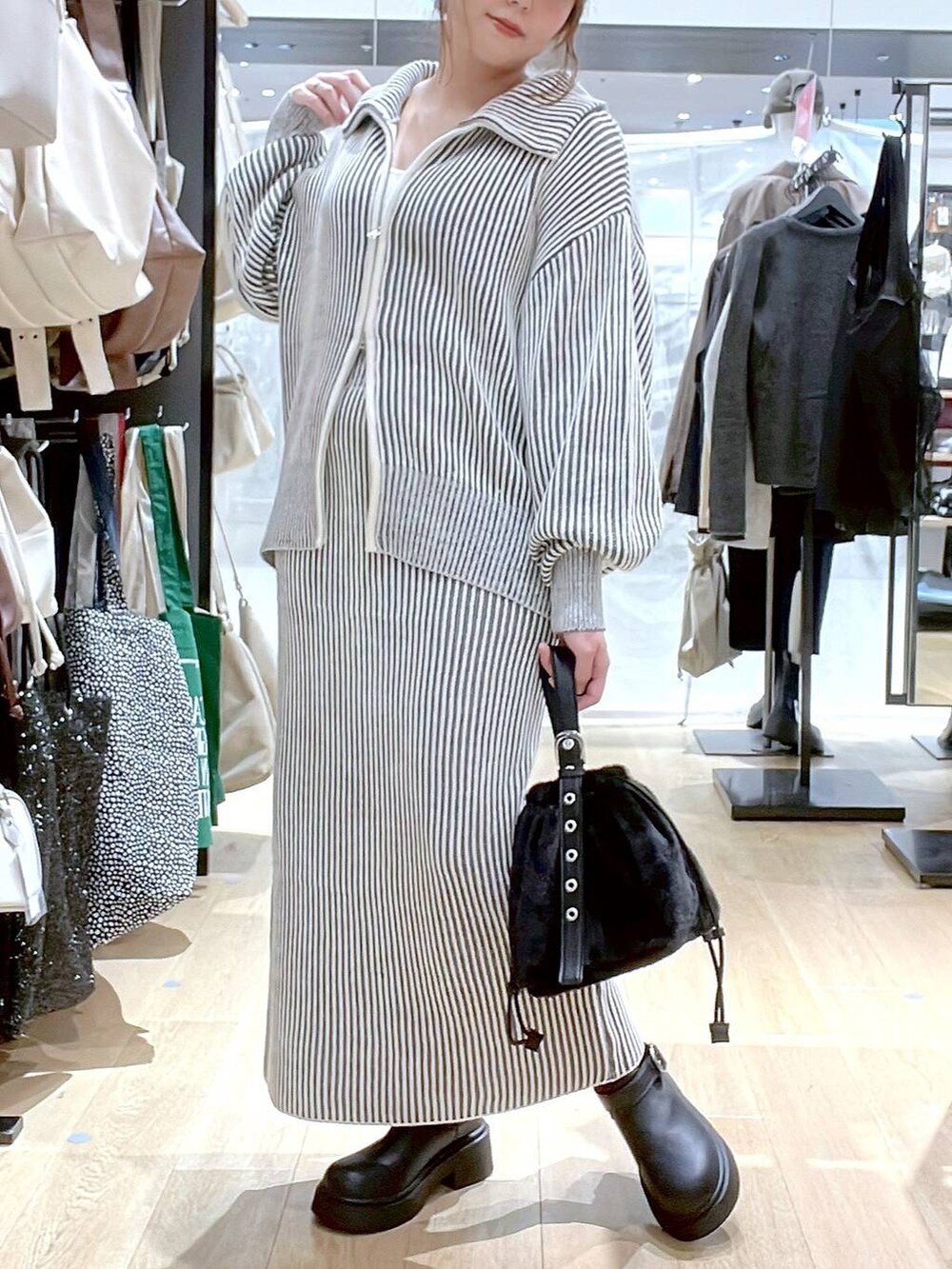 ホワイト系のタンクトップ、ブラック系のハンドバッグ、ベージュ系のスカートを着用したレディースの秋コーディネートの3枚目の写真