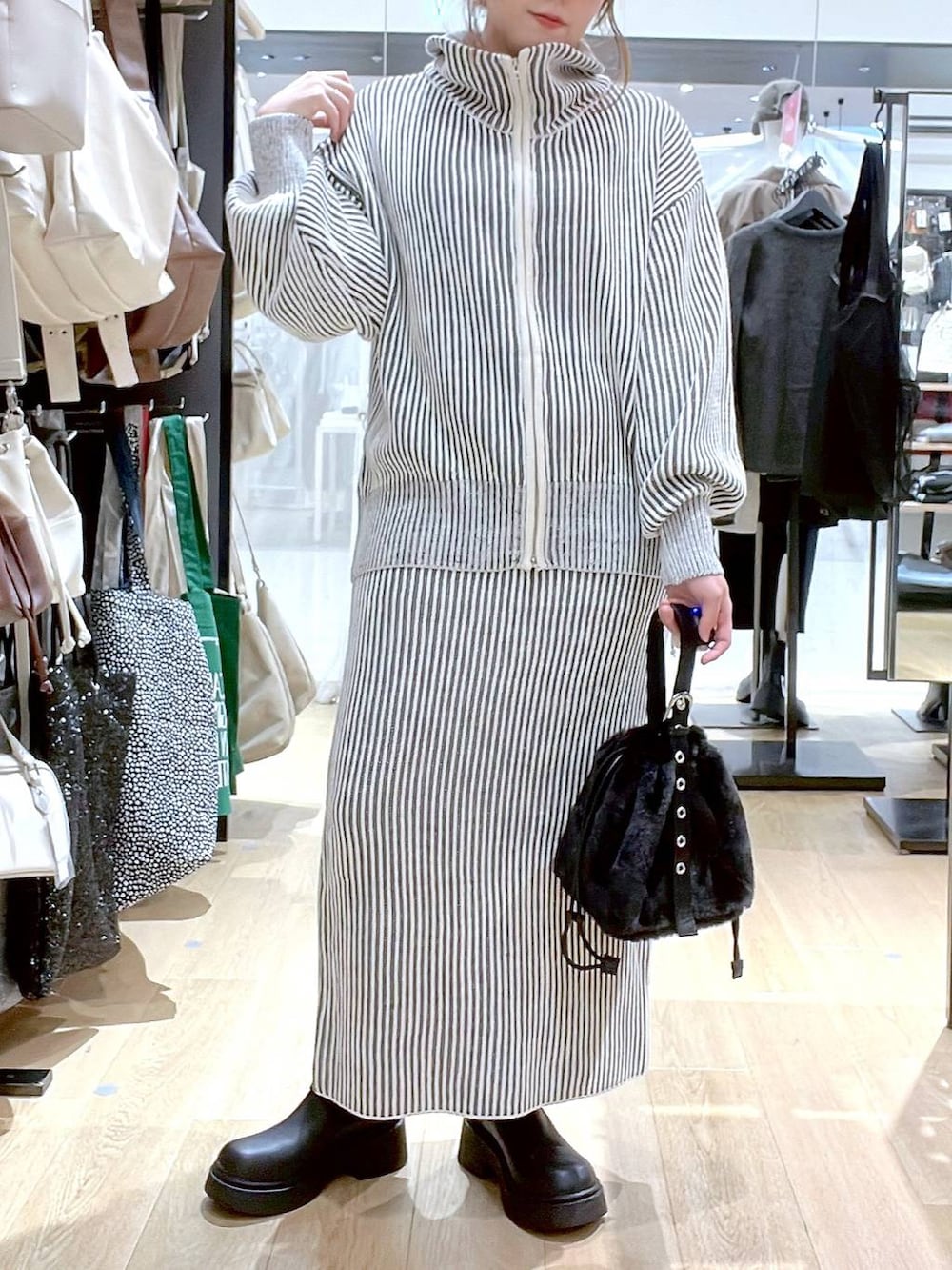 ホワイト系のタンクトップ、ブラック系のハンドバッグ、ベージュ系のスカートを着用したレディースの秋コーディネートの9枚目の写真