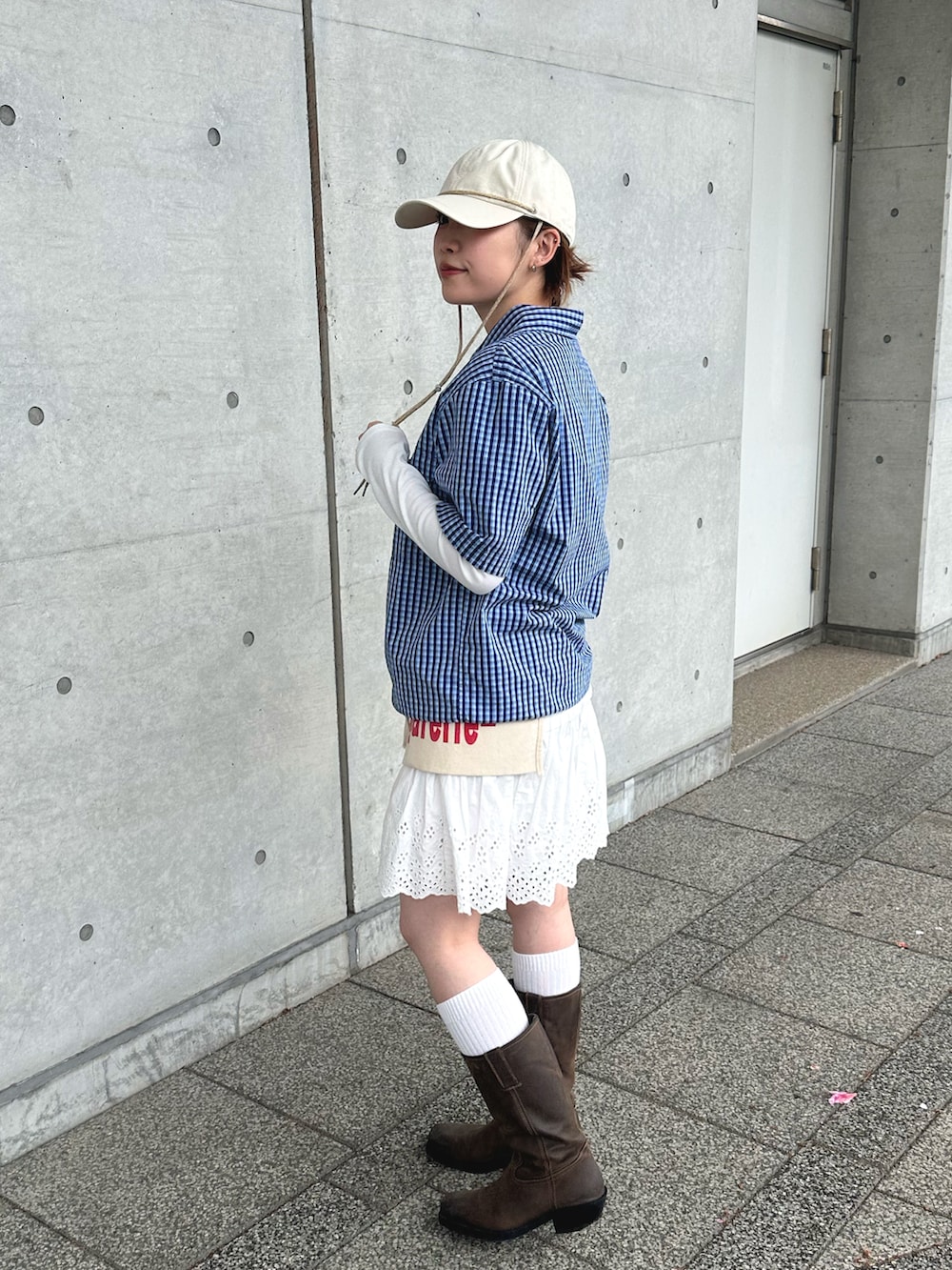 ブルー系のシャツ/ブラウス、ホワイト系のスカート、ブラウン系のブーツを着用したレディースの春コーディネートの2枚目の写真