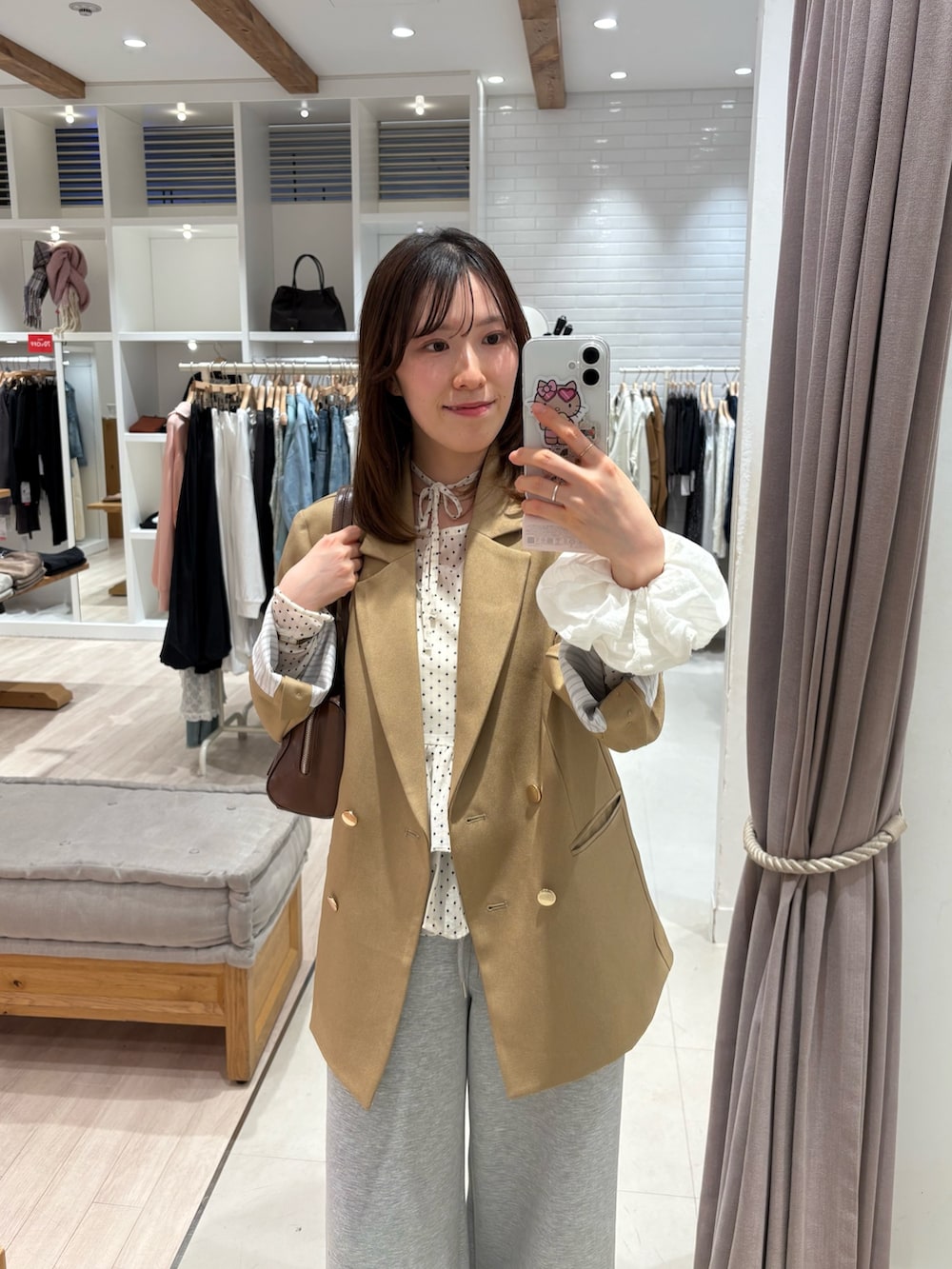 ベージュ系のテーラードジャケット、グレー系のスウェットパンツ、ブラウン系のブーツを着用したレディースの春コーディネートの2枚目の写真