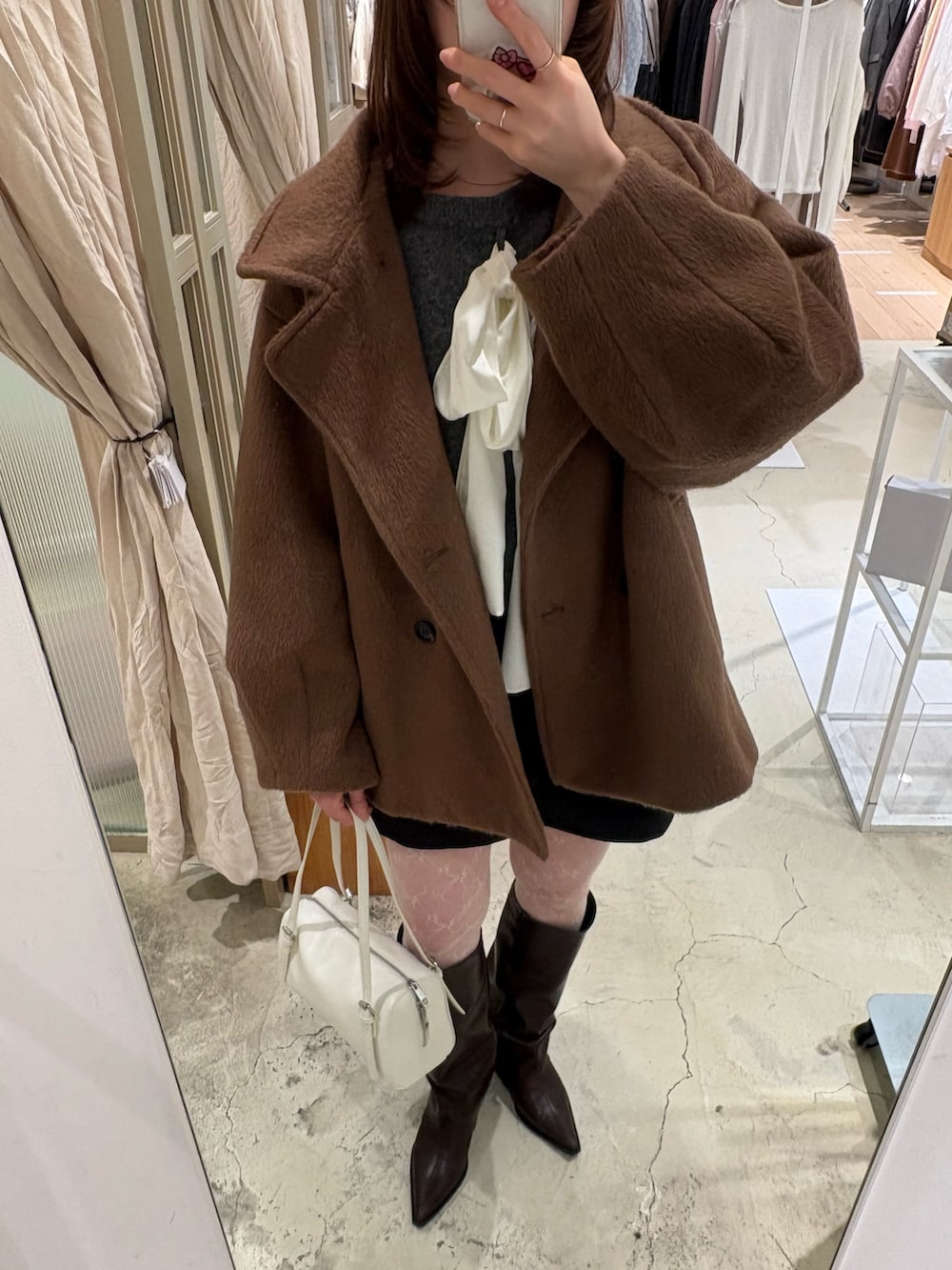 グレー系のニット/セーター、ブルー系のデニムパンツ、ブラウン系のパンプスを着用したレディースの冬コーディネートの5枚目の写真