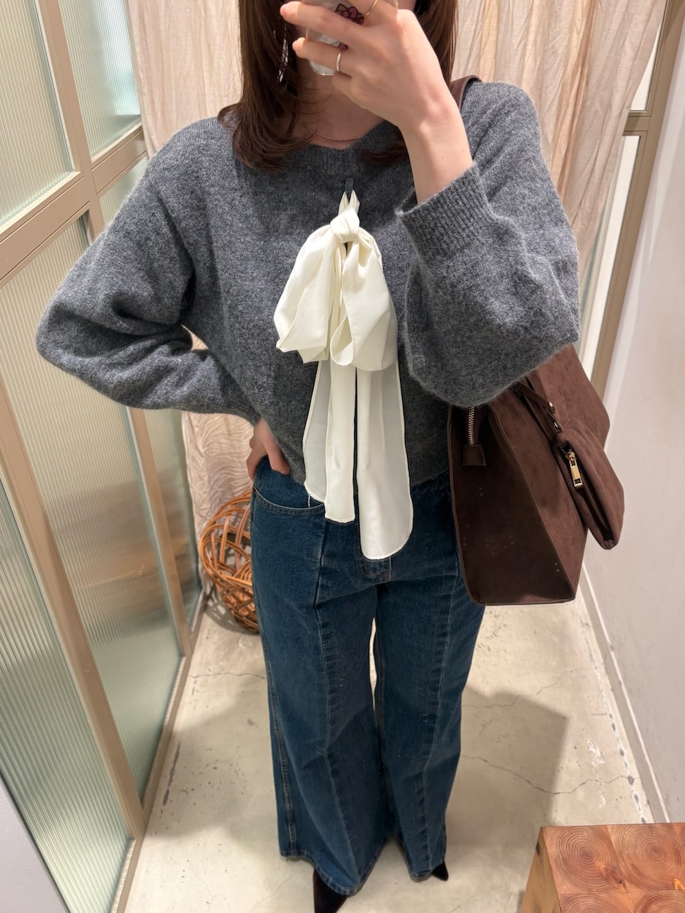 グレー系のニット/セーター、ブルー系のデニムパンツ、ブラウン系のパンプスを着用したレディースの冬コーディネートの2枚目の写真