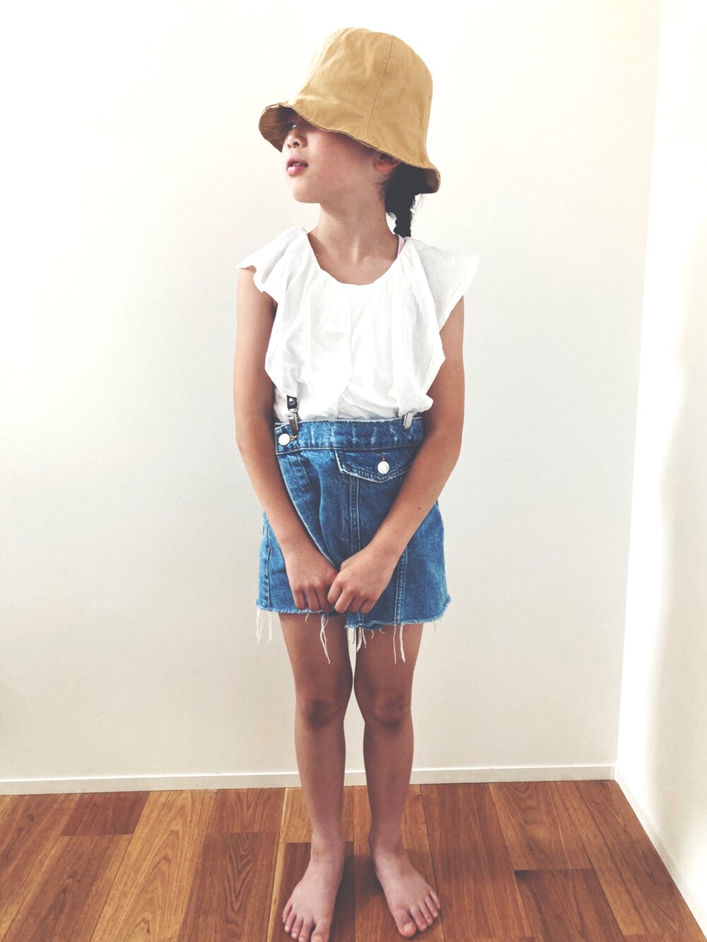 ホワイト系のタンクトップ、ブルー系のデニムパンツ、ベージュ系のハットを着用したレディースの夏コーディネートの2枚目の写真