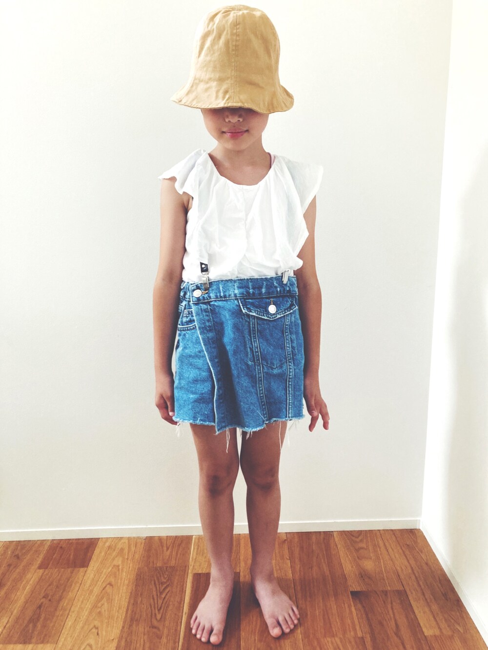 ホワイト系のタンクトップ、ブルー系のデニムパンツ、ベージュ系のハットを着用したレディースの夏コーディネートの3枚目の写真