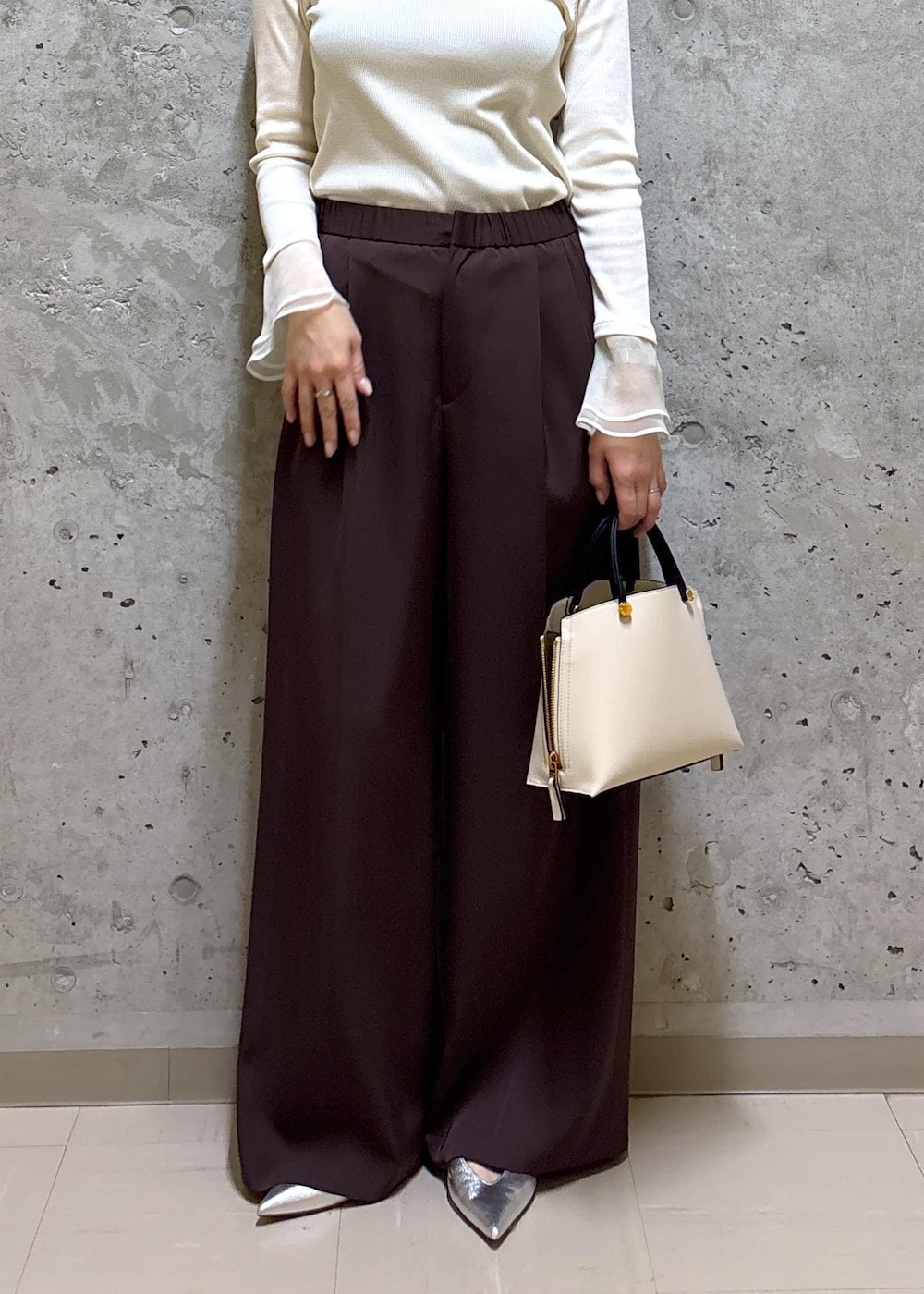 シルバー系のパンプス、ホワイト系のハンドバッグ、ブラウン系のテーラードジャケットを着用したレディースの春コーディネートの6枚目の写真