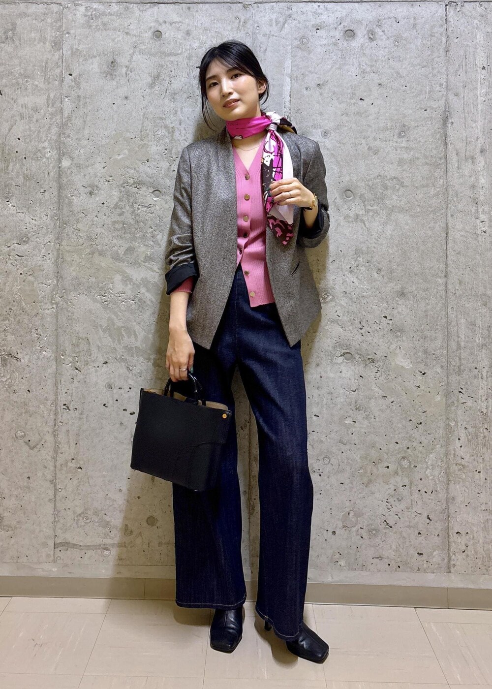 ブラック系のハンドバッグ、ブラック系のステンカラーコート、ブルー系のデニムパンツを着用したレディースの秋コーディネートの7枚目の写真