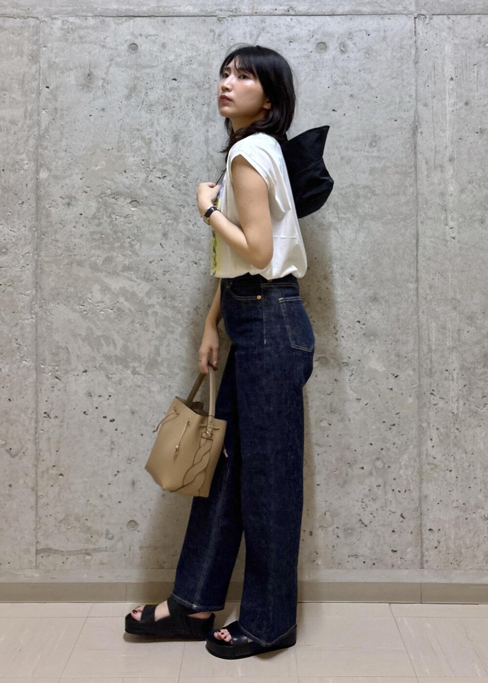 ブラック系のサンダル、ホワイト系のTシャツ/カットソー、ブルー系のデニムパンツを着用したレディースの夏コーディネートの3枚目の写真