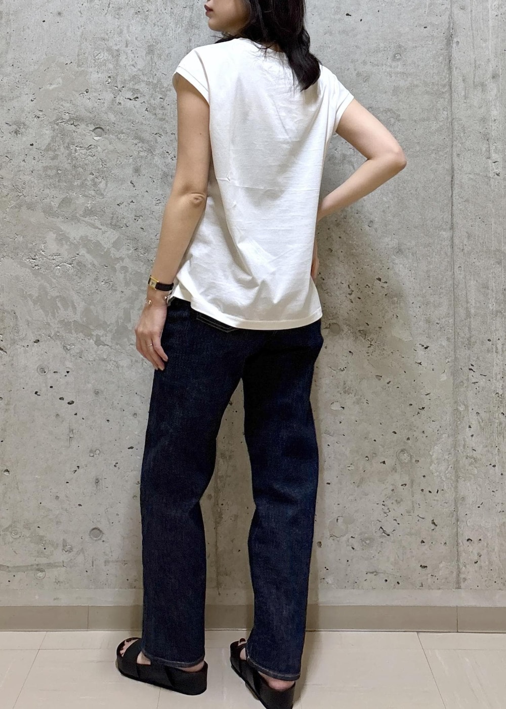 ブラック系のサンダル、ホワイト系のTシャツ/カットソー、ブルー系のデニムパンツを着用したレディースの夏コーディネートの7枚目の写真