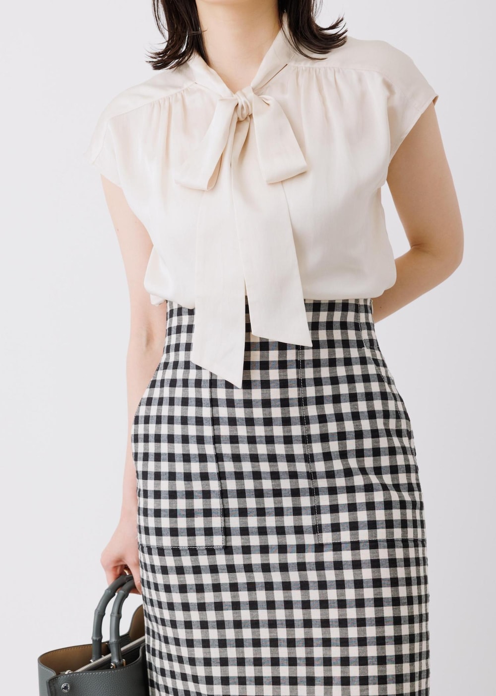 ブラック系のスカート、ベージュ系のシャツ/ブラウス、グレー系のトートバッグを着用したレディースの春コーディネートの3枚目の写真