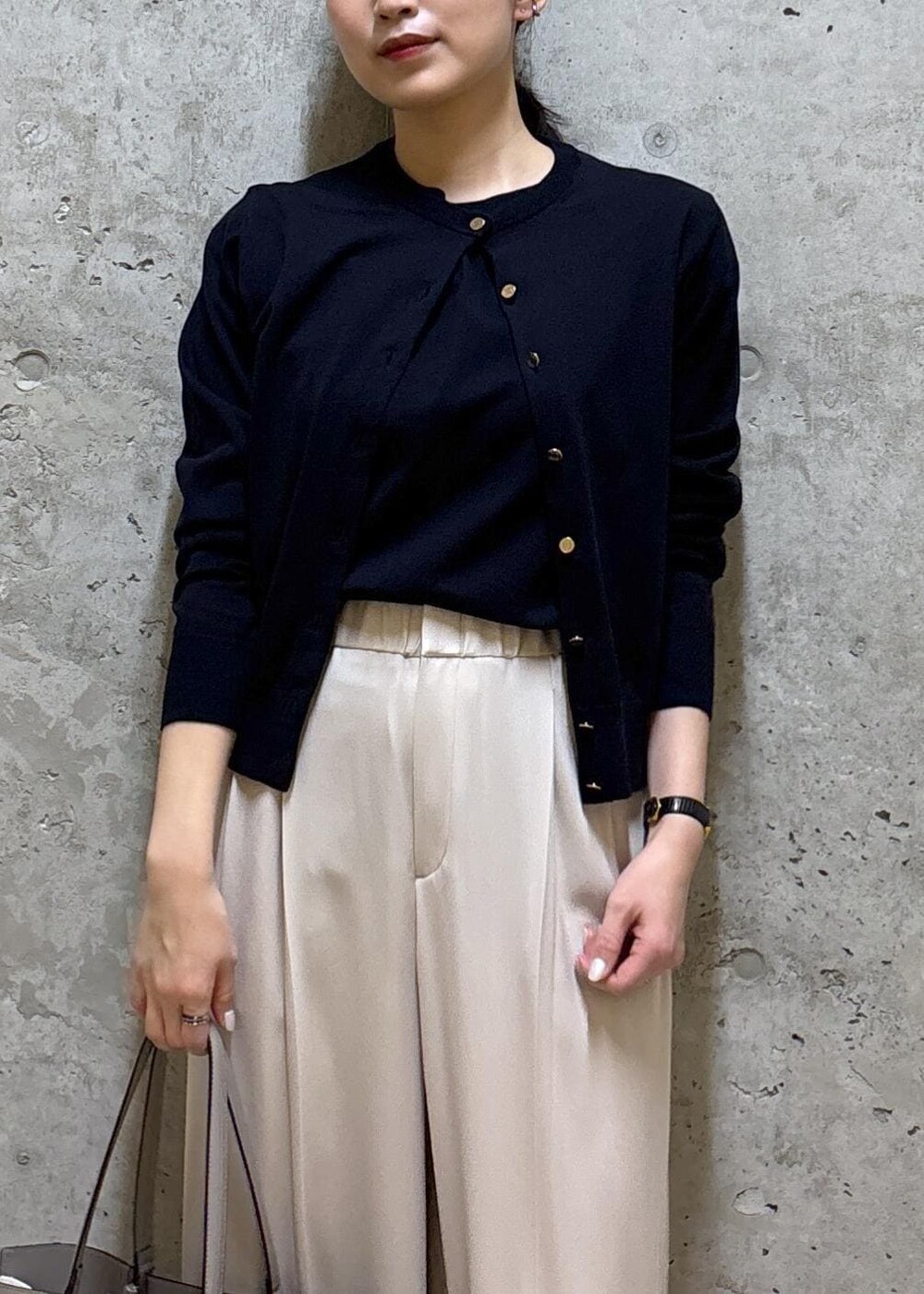 グレー系のトートバッグ、ブラック系のパンプス、ブルー系のニット/セーターを着用したレディースの春コーディネートの2枚目の写真