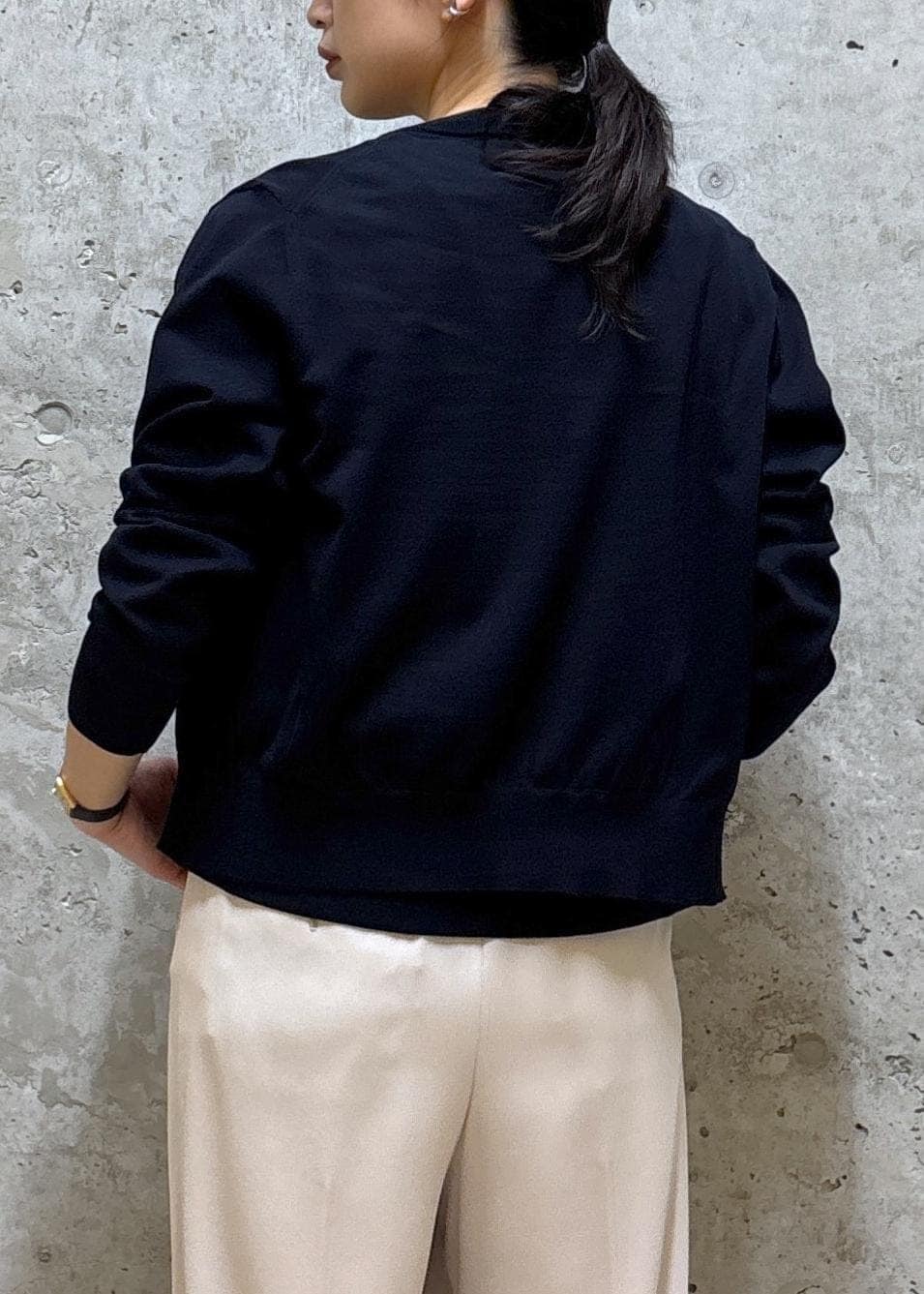 グレー系のトートバッグ、ブラック系のパンプス、ブルー系のニット/セーターを着用したレディースの春コーディネートの6枚目の写真