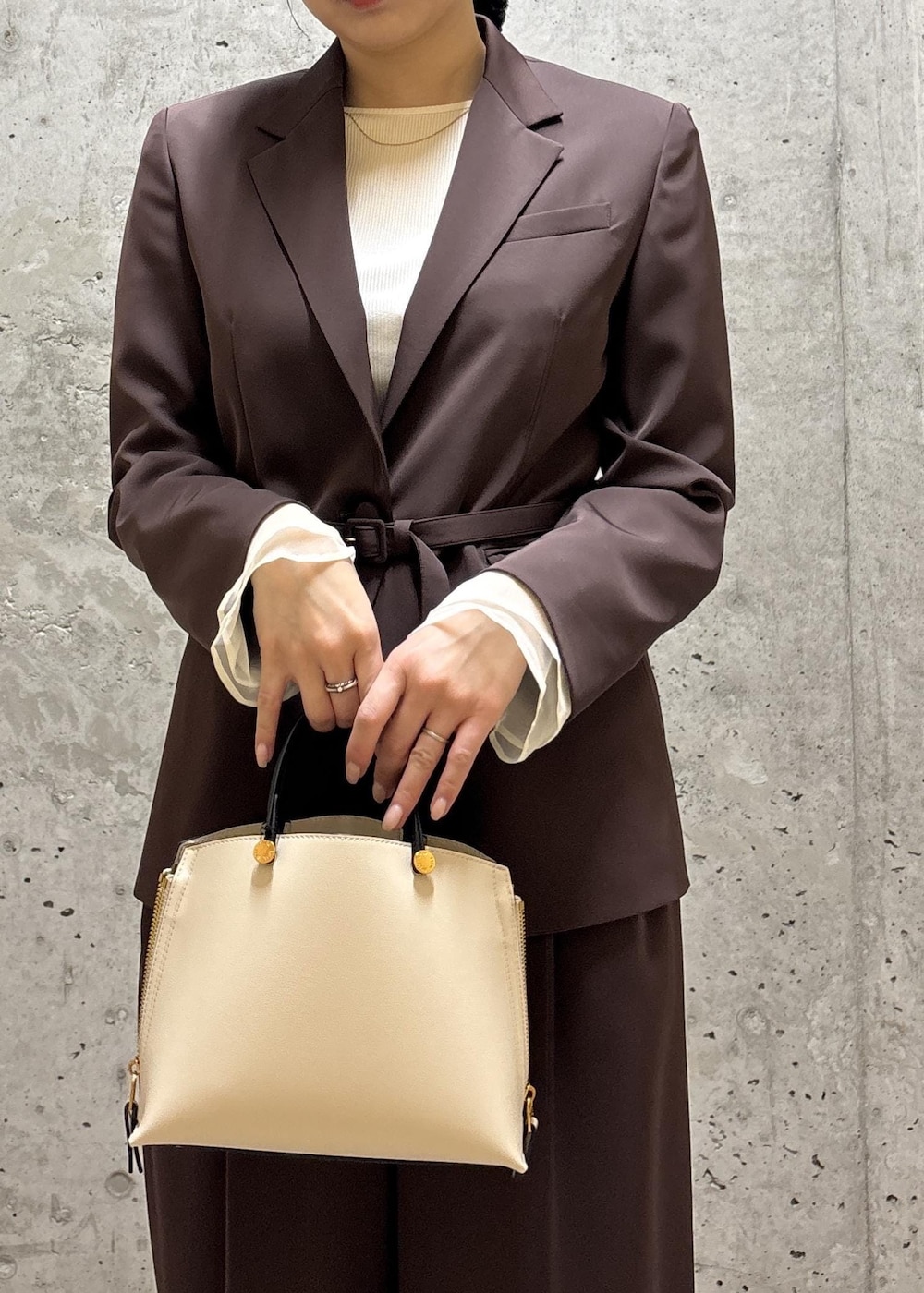 シルバー系のパンプス、ホワイト系のハンドバッグ、ブラウン系のテーラードジャケットを着用したレディースの春コーディネートの4枚目の写真