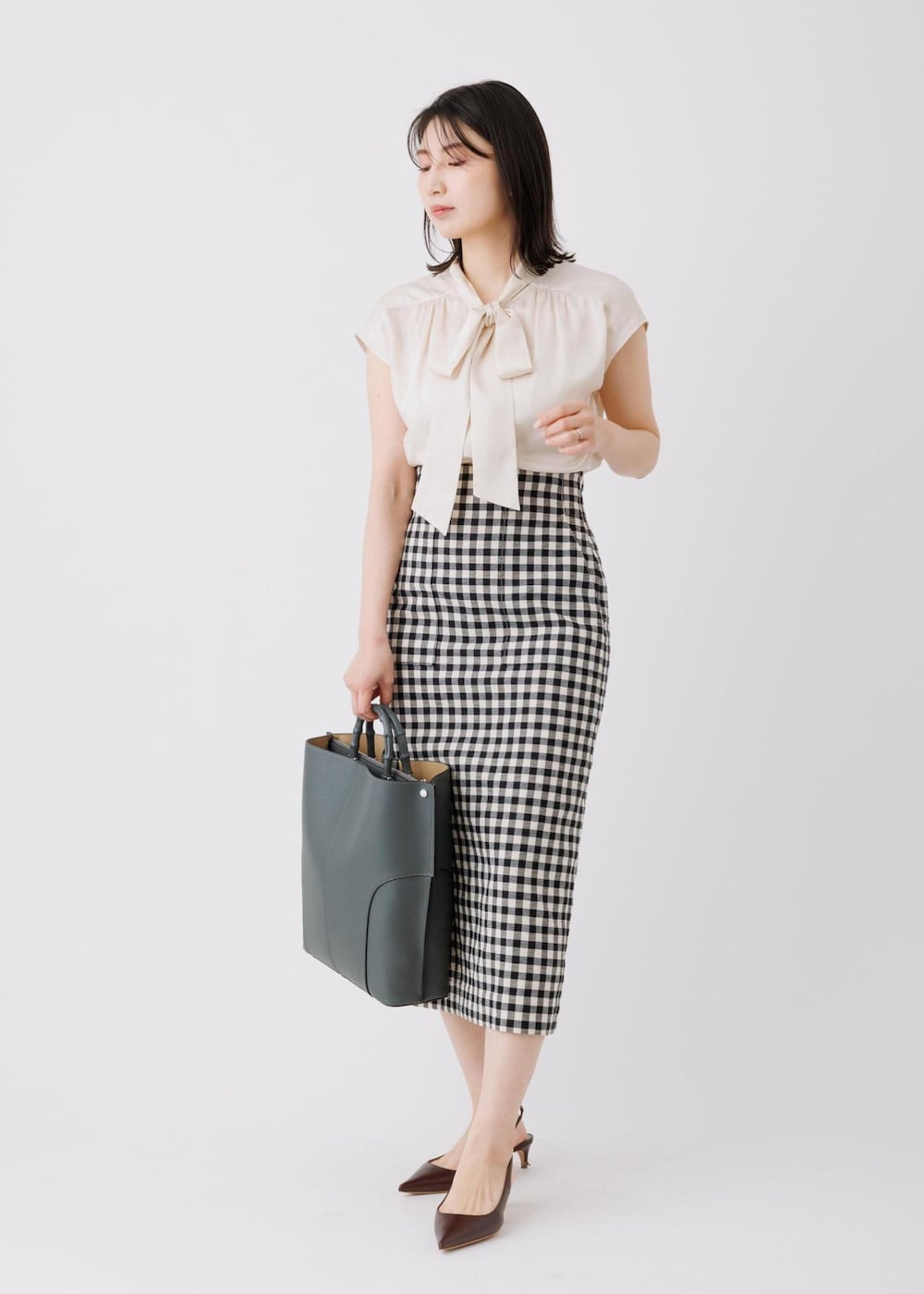ブラック系のスカート、ベージュ系のシャツ/ブラウス、グレー系のトートバッグを着用したレディースの春コーディネートの2枚目の写真
