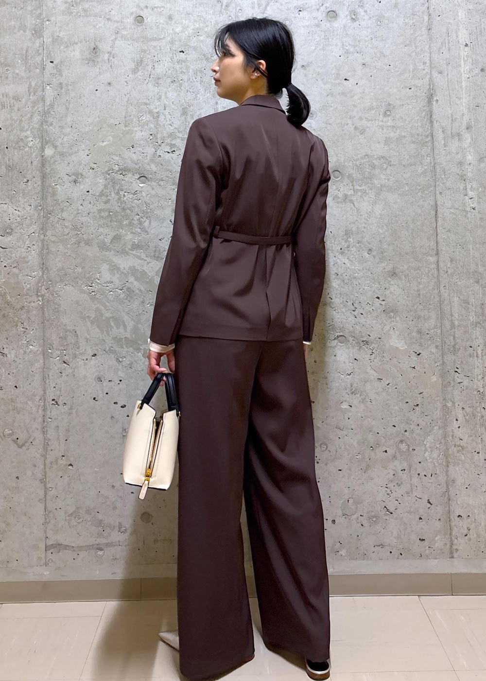 シルバー系のパンプス、ホワイト系のハンドバッグ、ブラウン系のテーラードジャケットを着用したレディースの春コーディネートの3枚目の写真