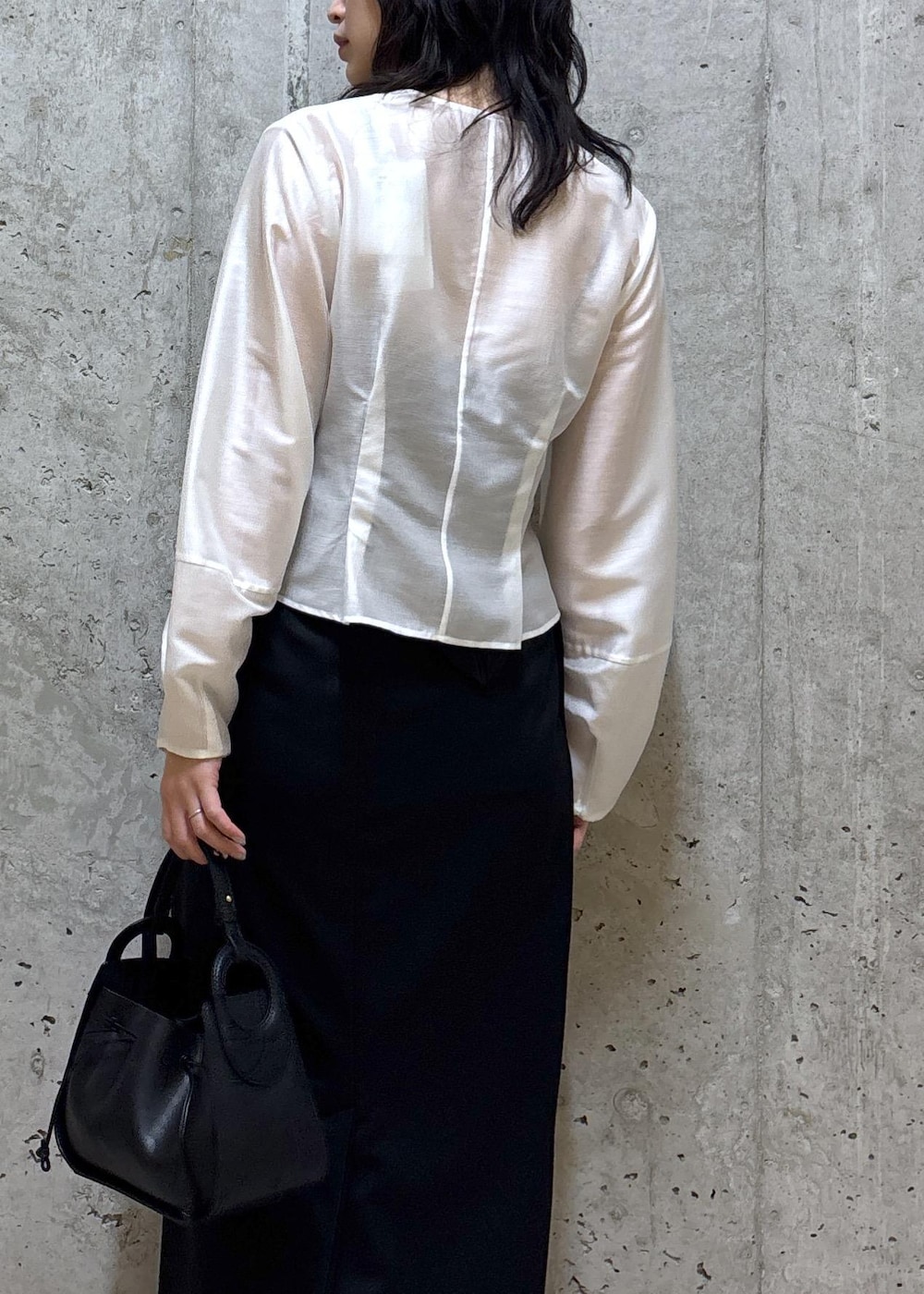 ブラック系のハンドバッグ、ブラック系のブーツ、ブラック系のスカートを着用したレディースの春コーディネートの6枚目の写真