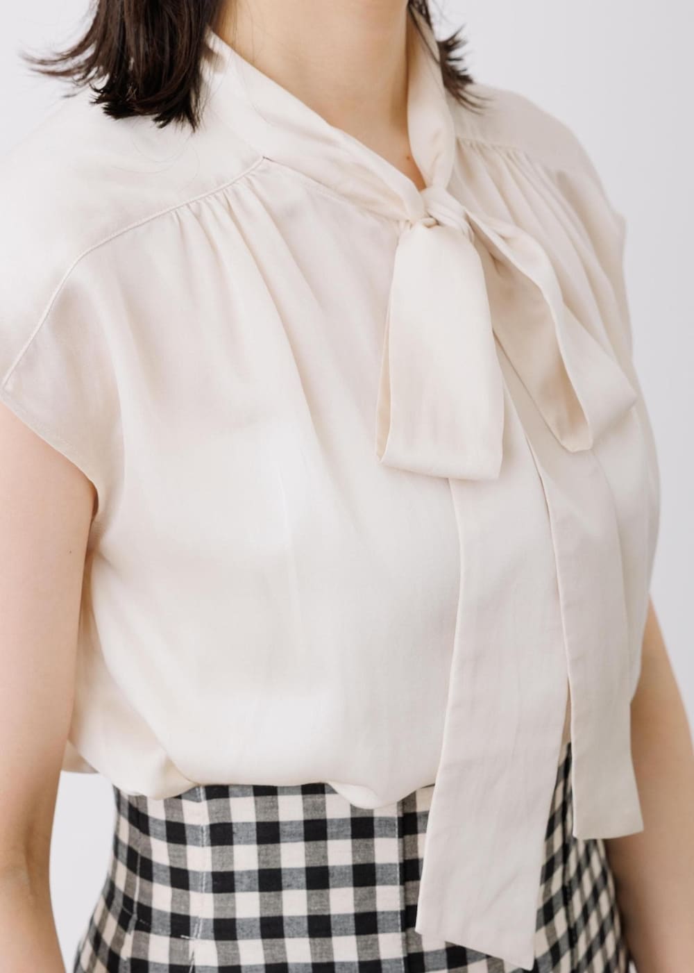 ブラック系のスカート、ベージュ系のシャツ/ブラウス、グレー系のトートバッグを着用したレディースの春コーディネートの4枚目の写真