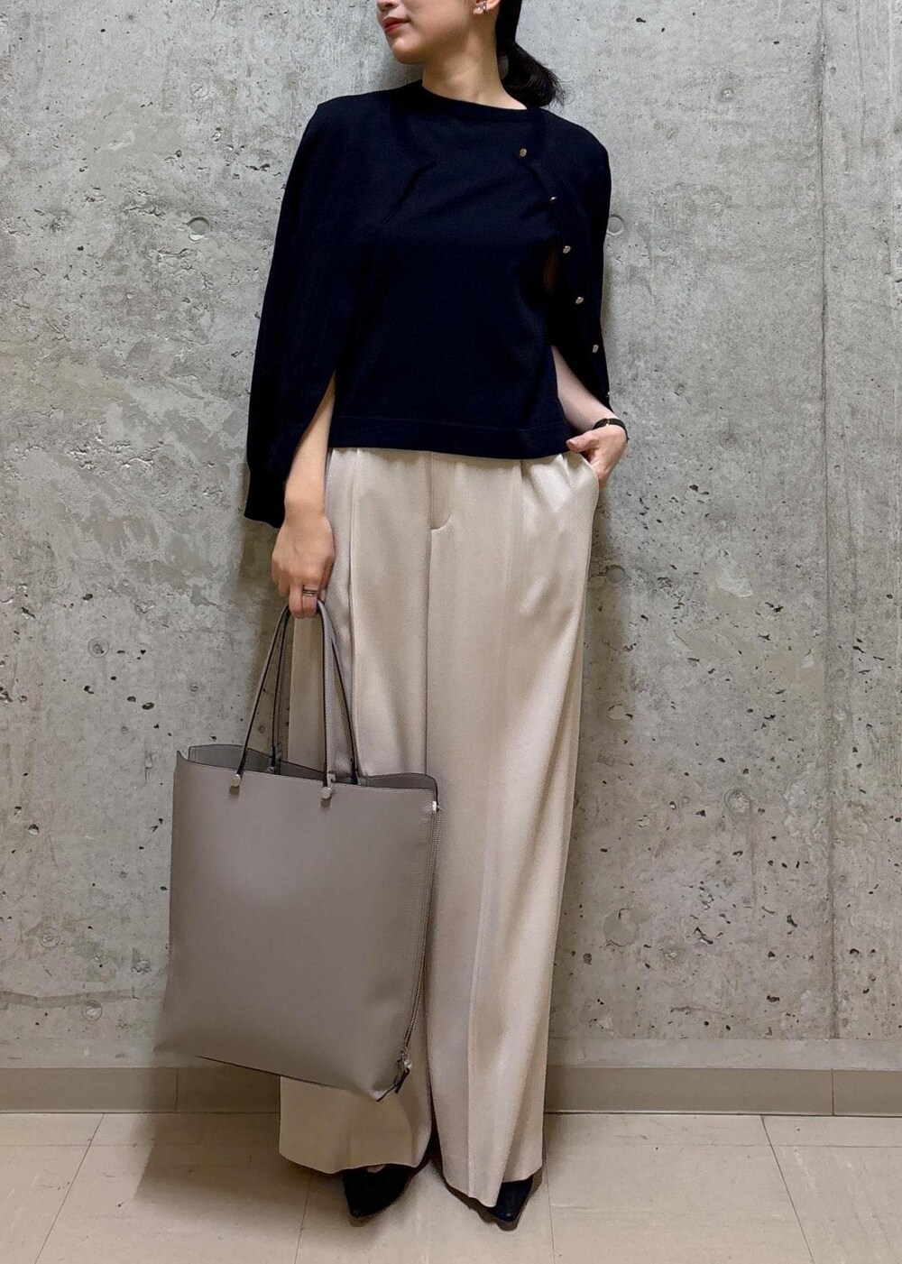 グレー系のトートバッグ、ブラック系のパンプス、ブルー系のニット/セーターを着用したレディースの春コーディネートの4枚目の写真