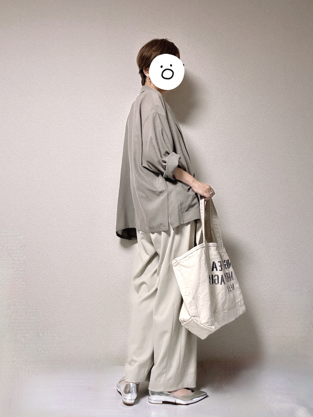 グリーン系のテーラードジャケット、ベージュ系のスラックス、ホワイト系のトートバッグを着用したレディースの夏コーディネートの2枚目の写真