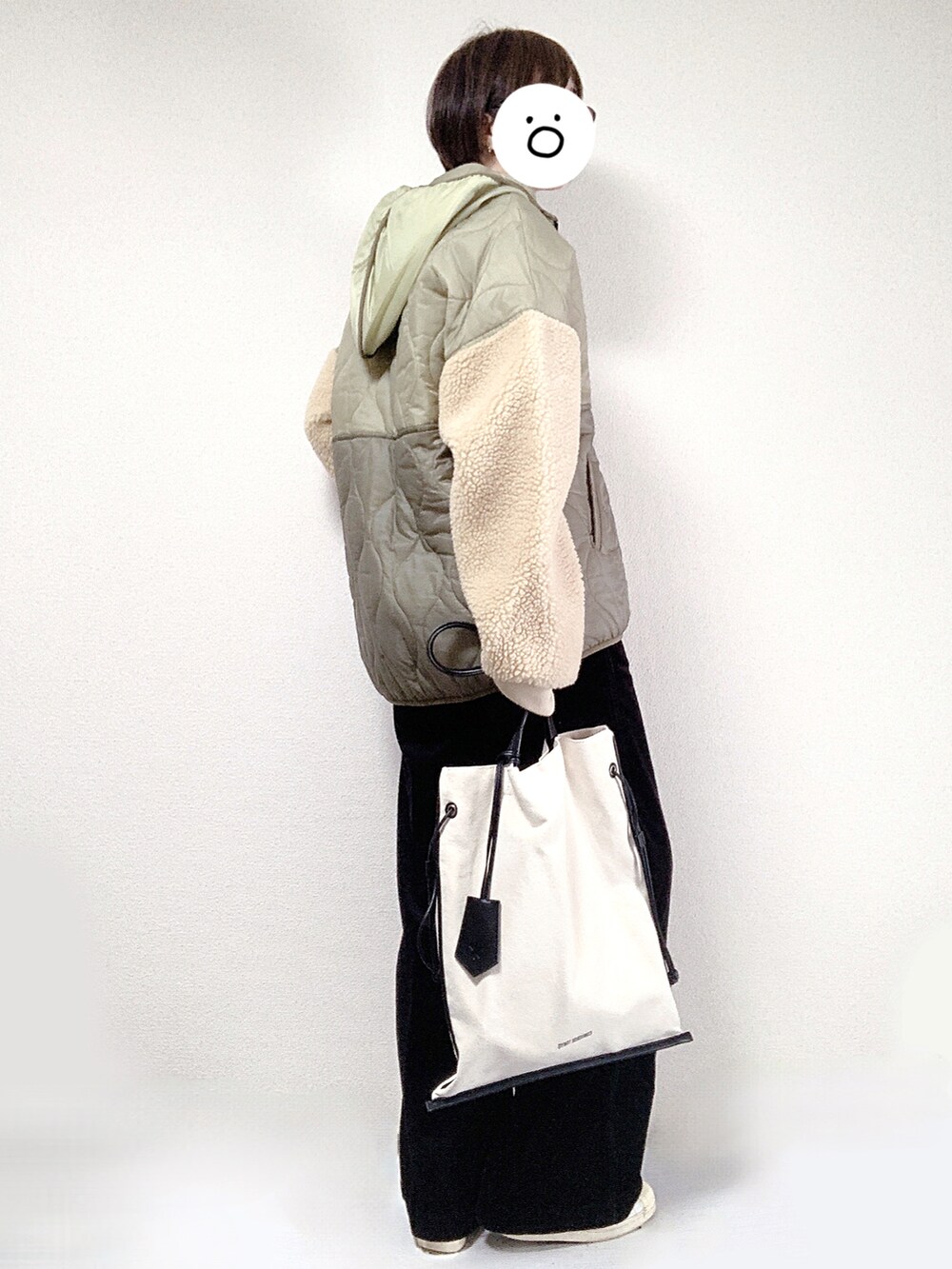 ブラック系のトートバッグ、ホワイト系のスニーカー、グリーン系のダウンジャケット/コートを着用したレディースの秋コーディネートの2枚目の写真