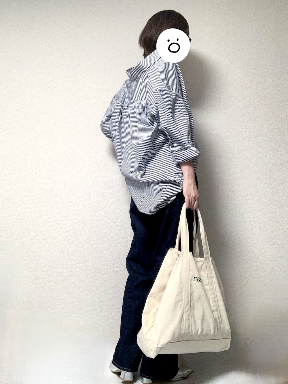 シルバー系のパンプス、ホワイト系のトートバッグ、ブルー系のデニムパンツを着用したレディースの春コーディネートの2枚目の写真