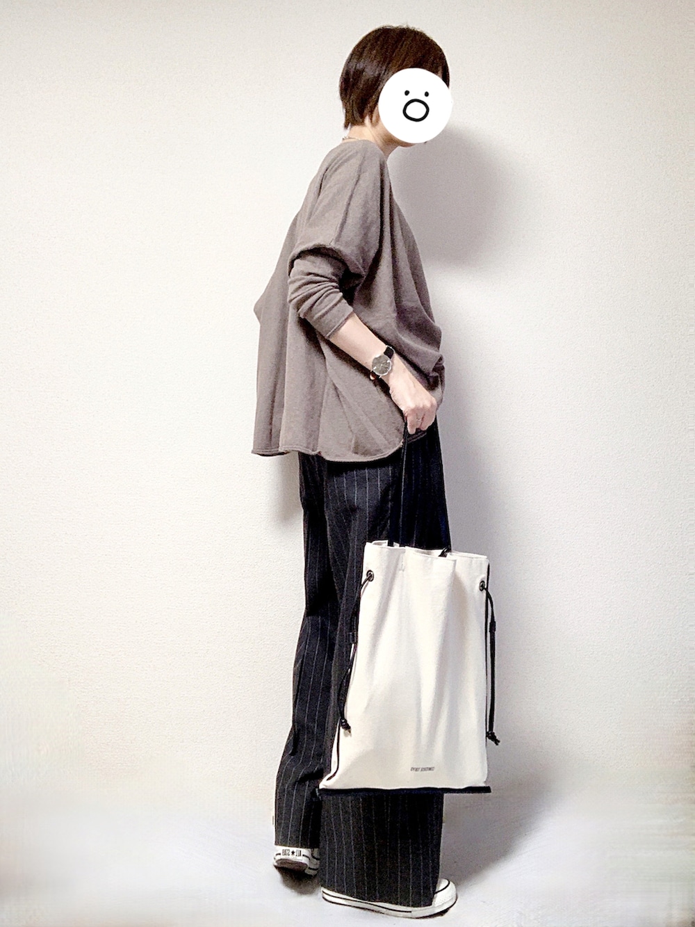 ホワイト系のスニーカー、グレー系のスラックス、ブラック系のトートバッグを着用したレディースの秋コーディネートの2枚目の写真