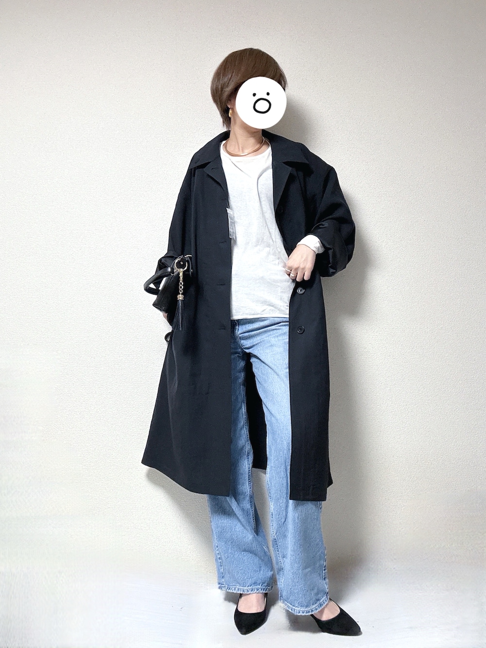 ブラック系のステンカラーコート、ホワイト系のニット/セーター、ブラック系のショルダーバッグを着用したレディースの春コーディネートの2枚目の写真