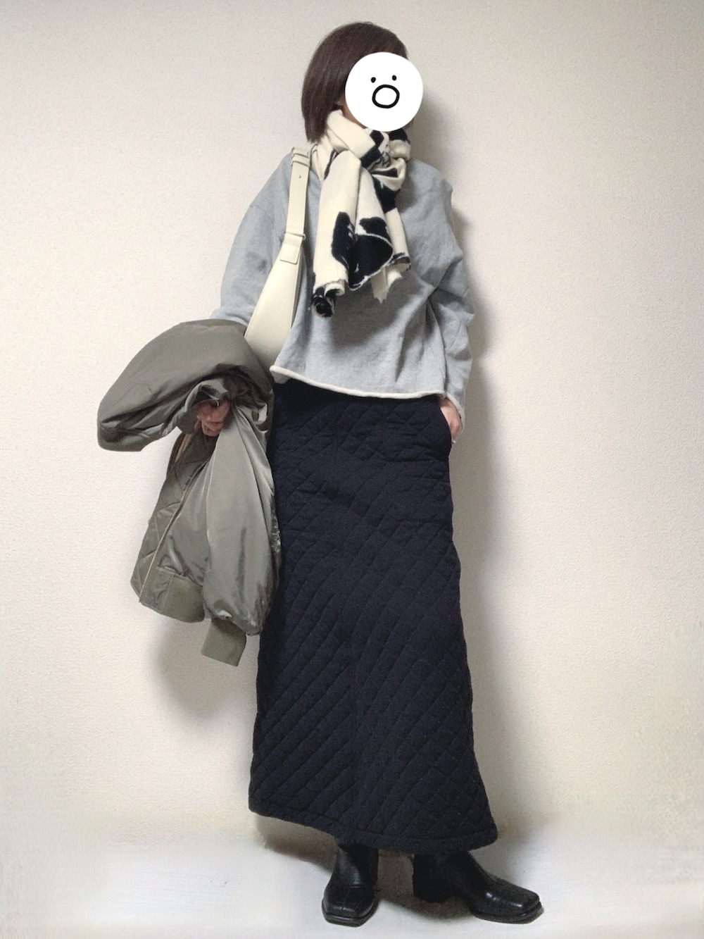 ブラック系のブーツ、ブラック系のスカート、ホワイト系のトートバッグを着用したレディースの冬コーディネートの2枚目の写真