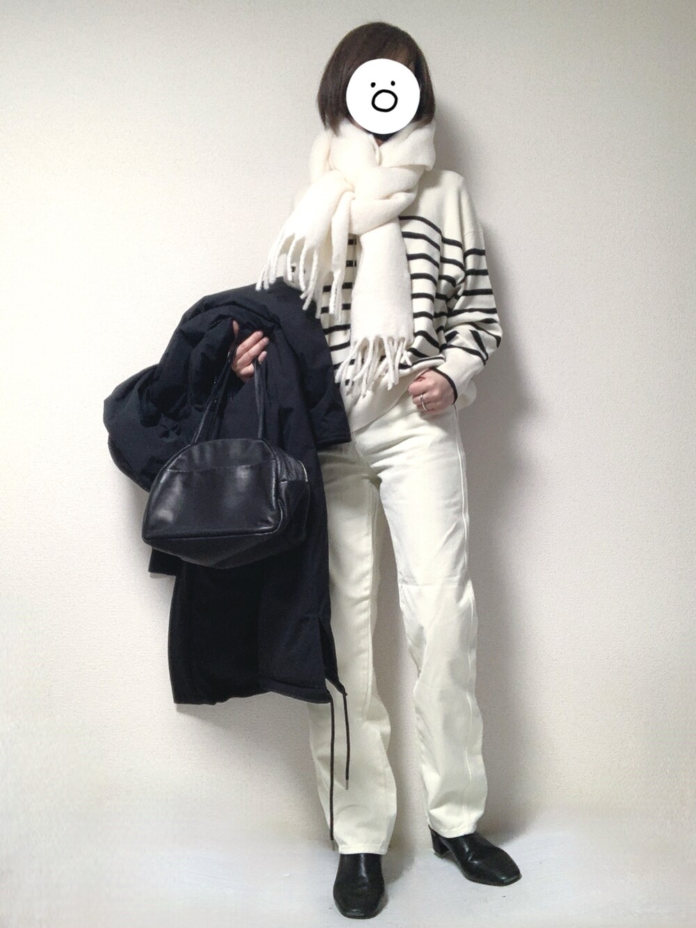 ブラック系のブーツ、ブラック系のトートバッグ、ホワイト系のデニムパンツを着用したレディースの冬コーディネートの3枚目の写真