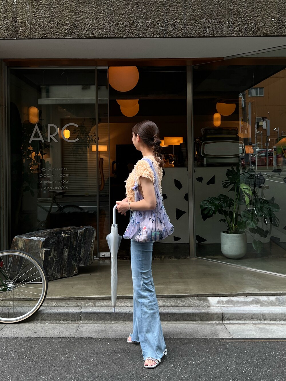 パープル系のトートバッグ、ブルー系のパンツ、シルバー系のその他シューズを着用したレディースの夏コーディネートの2枚目の写真