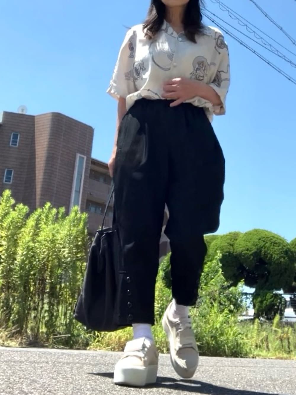 ホワイト系のシャツ/ブラウス、ブラック系のパンツ、ベージュ系のスニーカーを着用したレディースの夏コーディネートの2枚目の写真