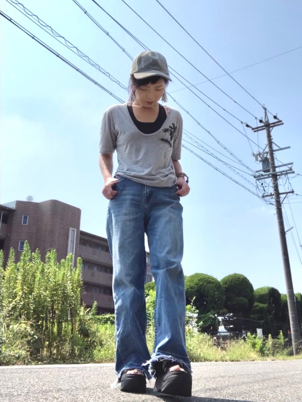 グレー系のTシャツ/カットソー、ブルー系のデニムパンツ、ブラック系のサンダルを着用したレディースの秋コーディネートの2枚目の写真