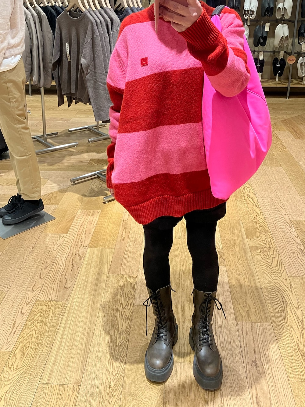 レッド系のニット/セーター、ブラック系のパンツ、ブラック系のハンドバッグを着用したレディースの冬コーディネートの3枚目の写真