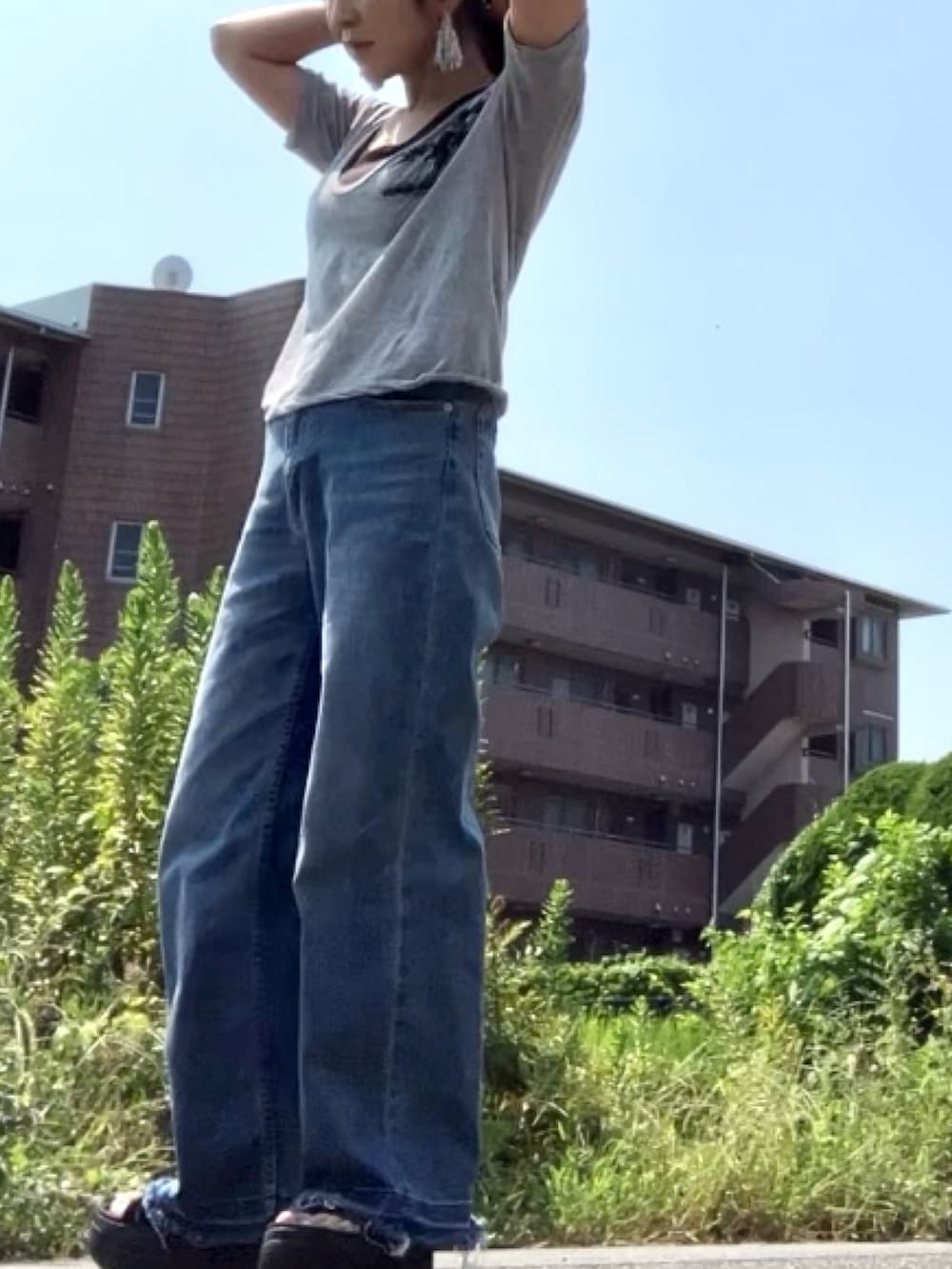 グレー系のTシャツ/カットソー、ブルー系のデニムパンツ、ブラック系のサンダルを着用したレディースの秋コーディネートの3枚目の写真