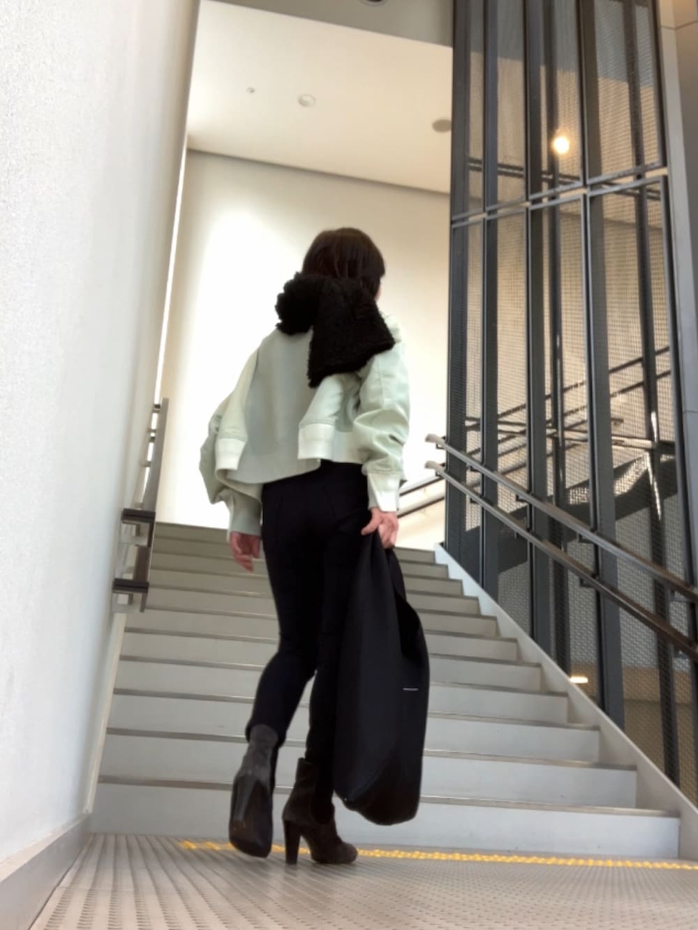 グリーン系のスウェット、ブラック系のパンツ、グレー系のブーツを着用したレディースの冬コーディネートの3枚目の写真
