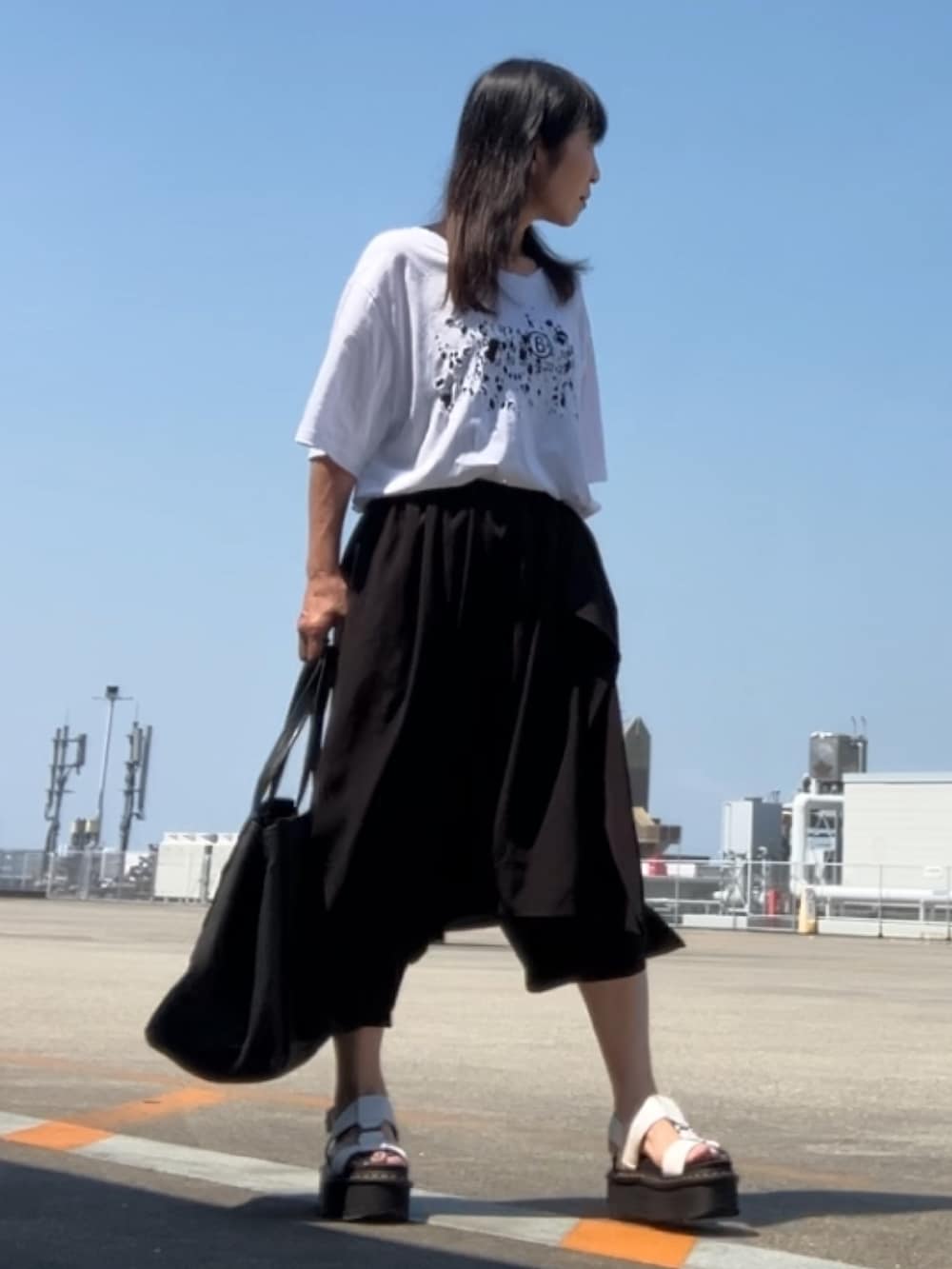 ホワイト系のTシャツ/カットソー、ブラック系のパンツ、グレー系のブーツを着用したレディースの夏コーディネートの3枚目の写真