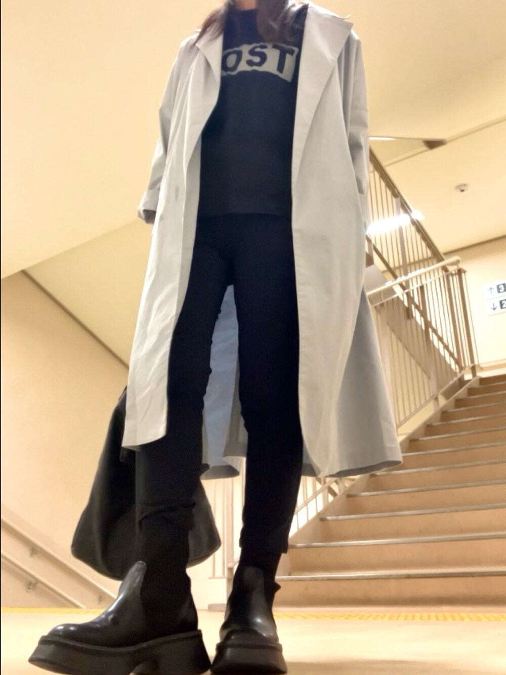 グレー系のチェスターコート、ブラック系のパンツ、ブラック系のブーツを着用したレディースの春コーディネートの3枚目の写真