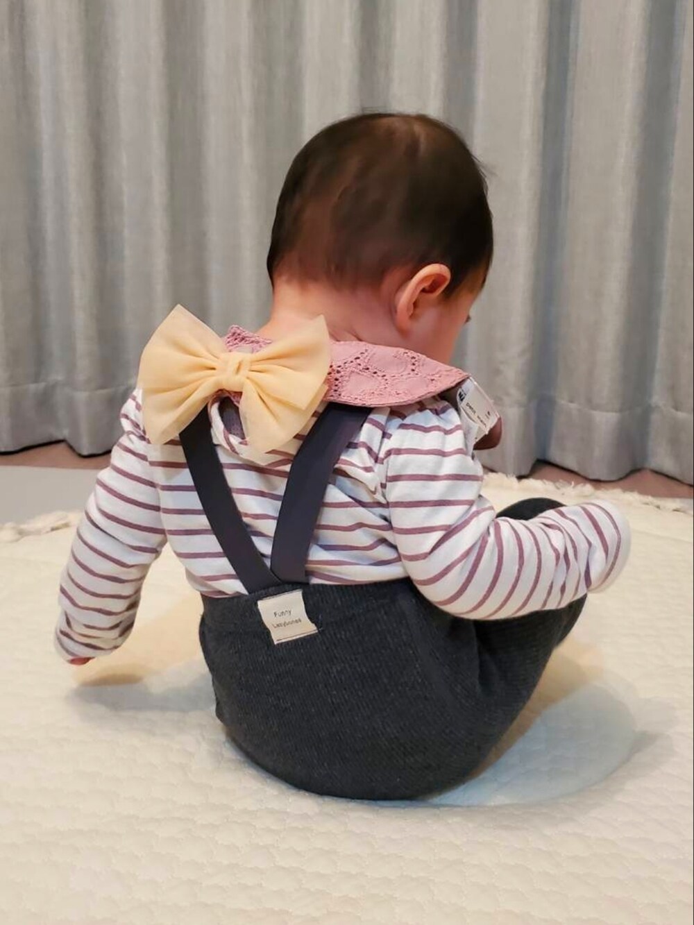 グレー系のパンツ、パープル系のTシャツ/カットソー、ピンク系のスタイ/よだれかけを着用したキッズの春コーディネートの2枚目の写真