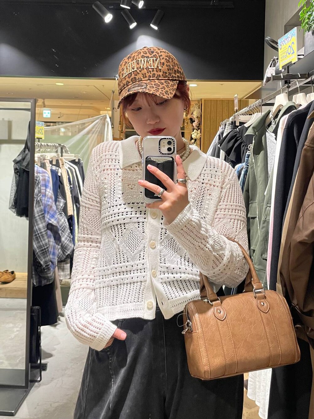 ブラック系のブーツ、ブラウン系のボストンバッグ、ブラック系のデニムパンツを着用したレディースの春コーディネートの4枚目の写真