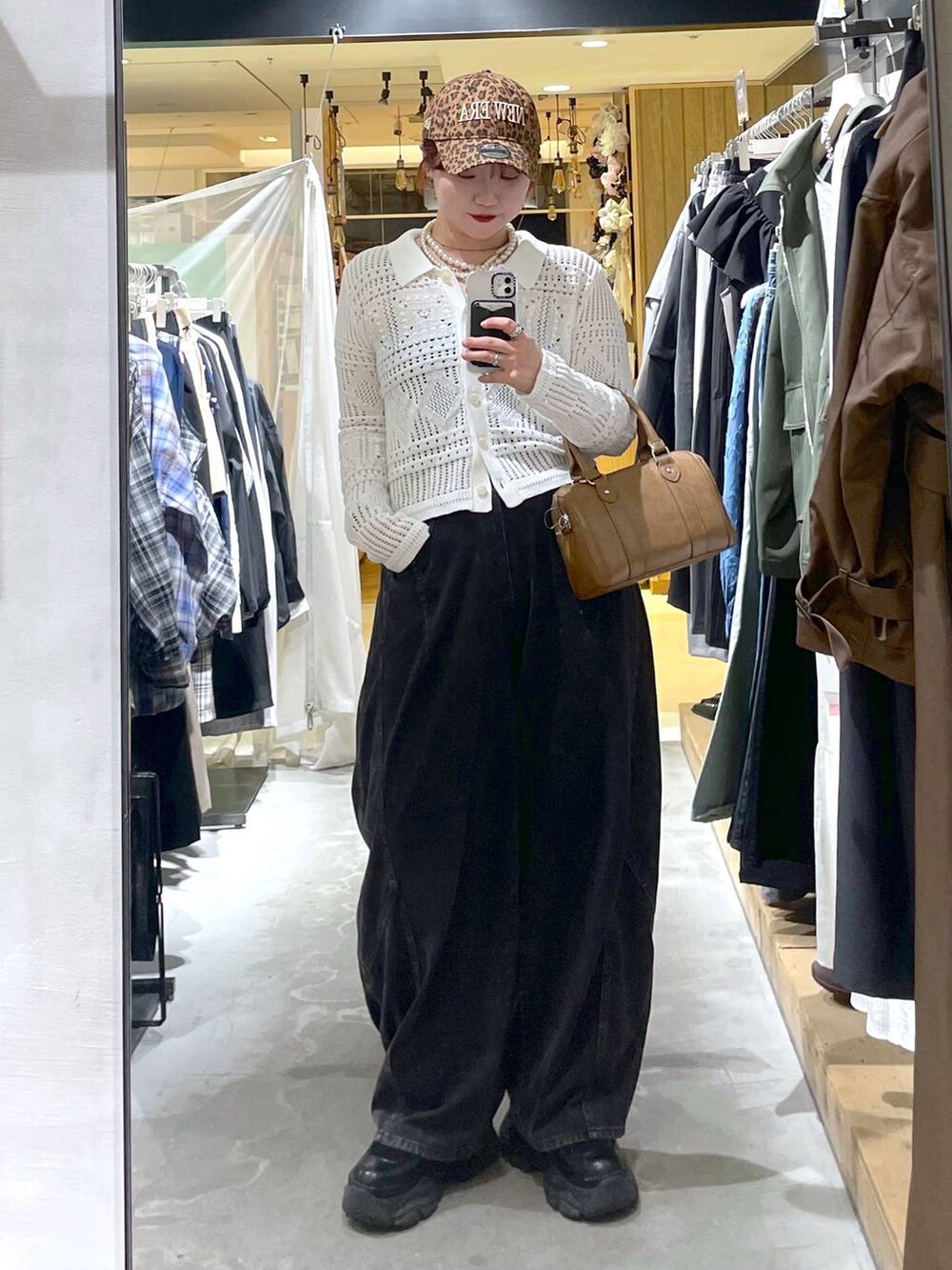 ブラック系のブーツ、ブラウン系のボストンバッグ、ブラック系のデニムパンツを着用したレディースの春コーディネートの2枚目の写真