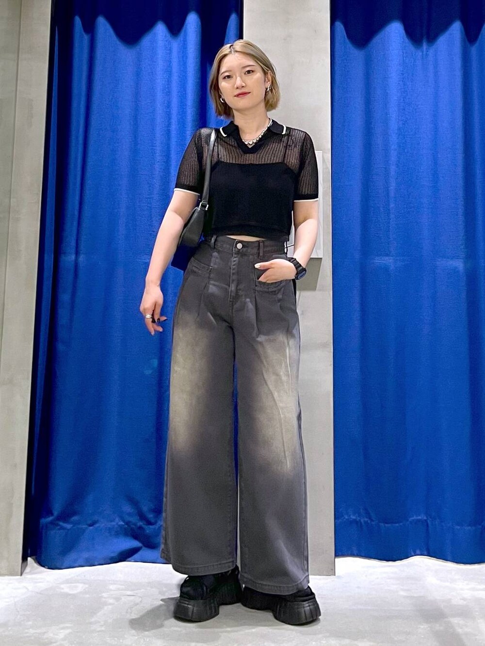 ブラック系のスニーカー、ブラック系のハンドバッグ、ブラック系のデニムパンツを着用したレディースの夏コーディネートの2枚目の写真