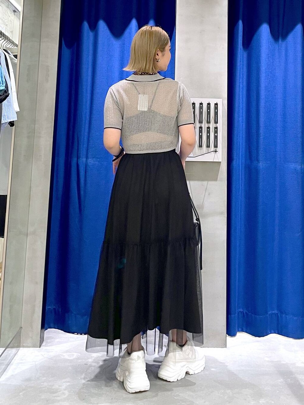 ホワイト系のスニーカー、ブラック系のハンドバッグ、ブラック系のニット/セーターを着用したレディースの夏コーディネートの3枚目の写真