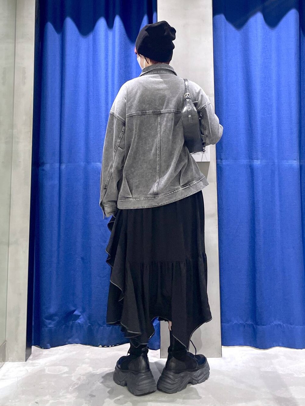 ブラック系のブーツ、ブラック系のスカート、ブラック系のハンドバッグを着用したレディースの冬コーディネートの5枚目の写真