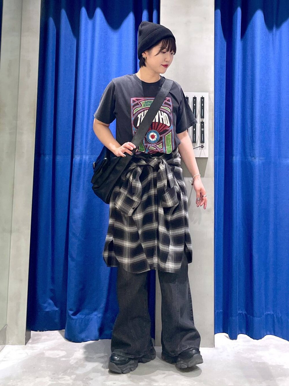 ブラック系のスニーカー、ブラック系のデニムパンツ、ブラック系のショルダーバッグを着用したレディースの秋コーディネートの2枚目の写真