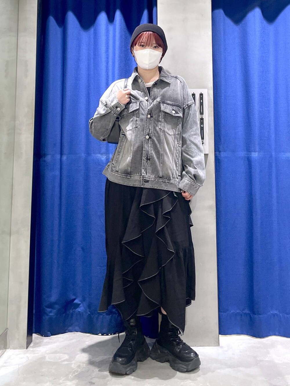 ブラック系のブーツ、ブラック系のスカート、ブラック系のハンドバッグを着用したレディースの冬コーディネートの2枚目の写真