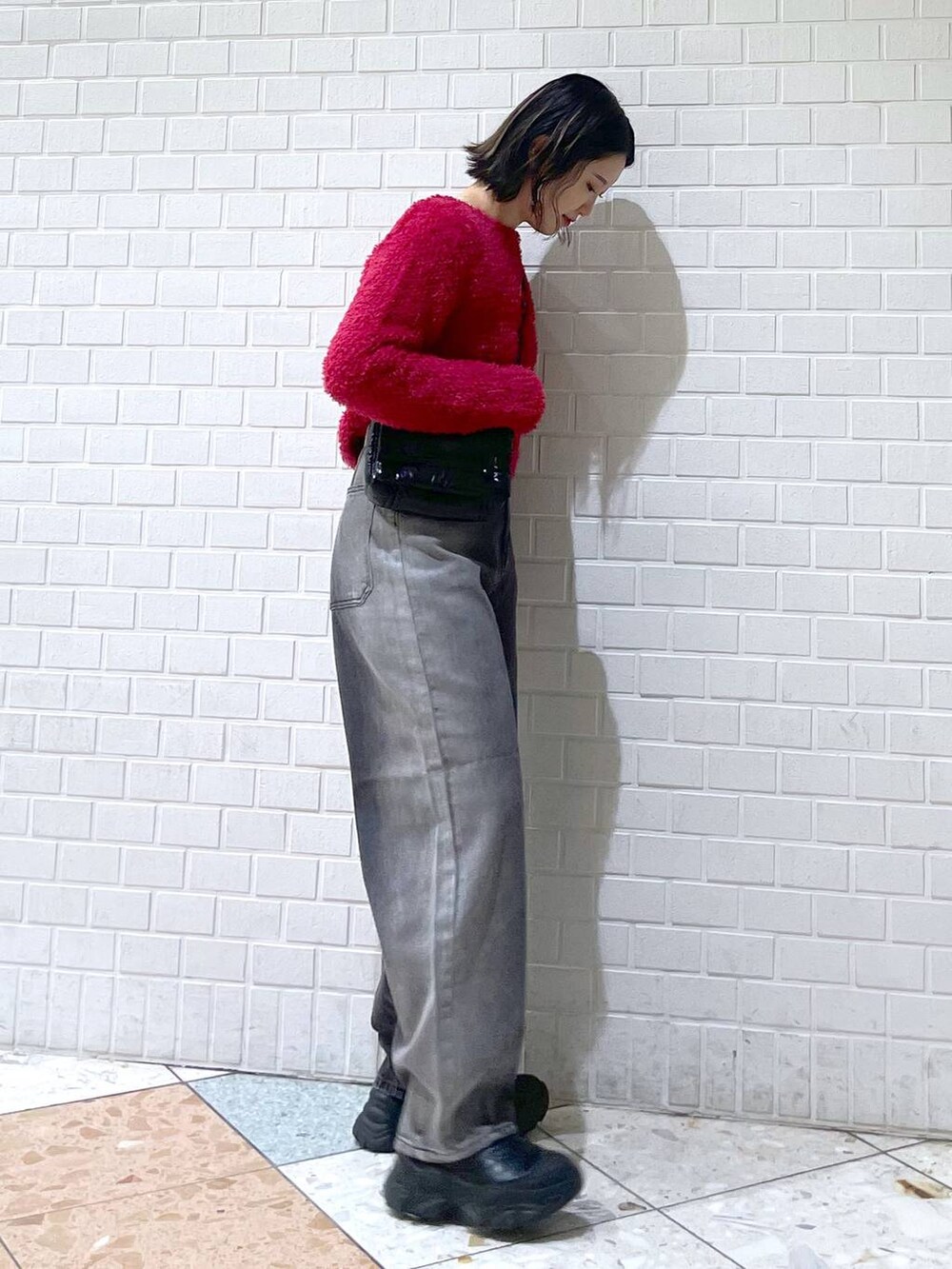 ブラック系のデニムパンツ、ブラック系のブーツ、ブラック系のショルダーバッグを着用したレディースの秋コーディネートの4枚目の写真