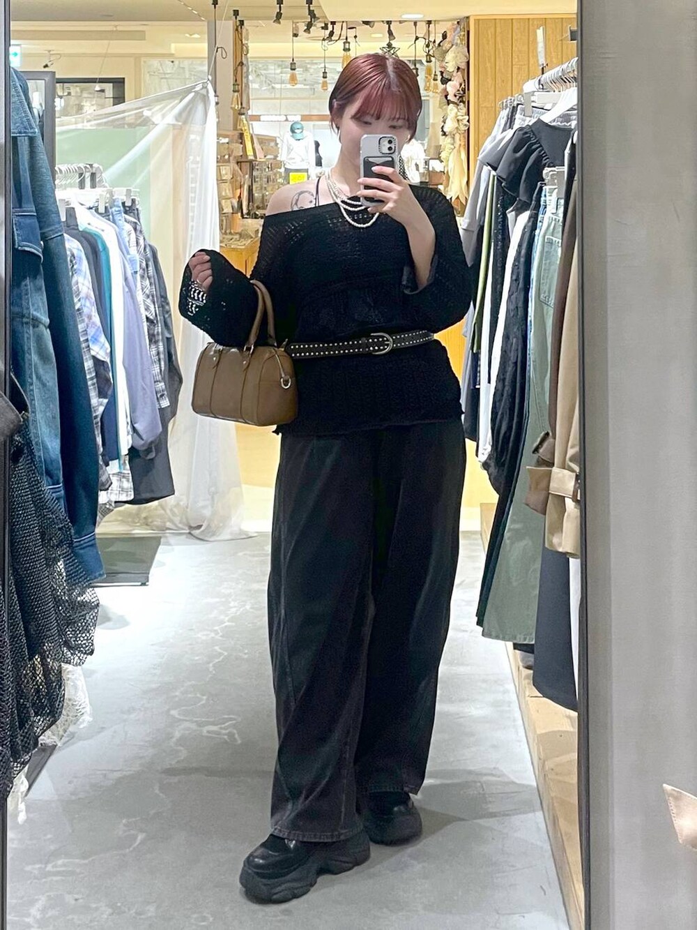 ブラック系のブーツ、ブラウン系のボストンバッグ、ブラック系のデニムパンツを着用したレディースの春コーディネートの2枚目の写真