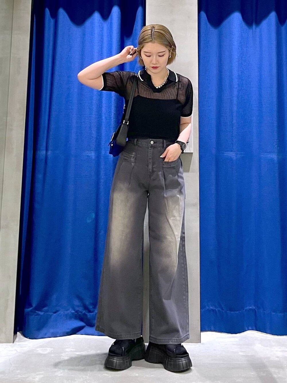 ブラック系のスニーカー、ブラック系のハンドバッグ、ブラック系のデニムパンツを着用したレディースの夏コーディネートの3枚目の写真