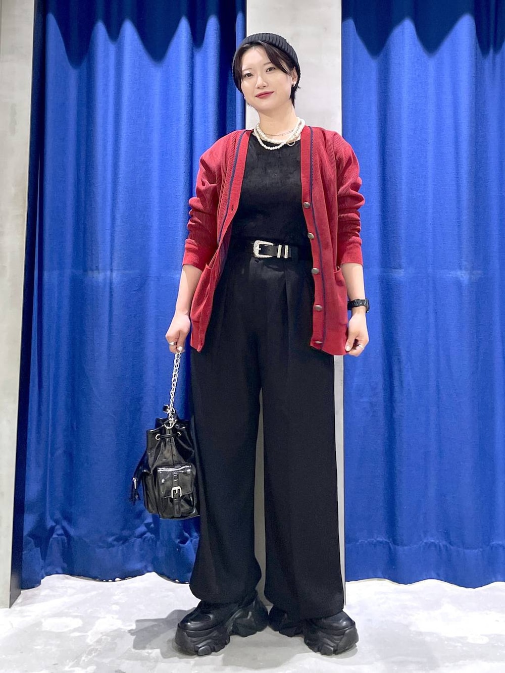 ブラック系のスニーカー、ブラック系のショルダーバッグ、レッド系のカーディガン/ボレロを着用したレディースの秋コーディネートの3枚目の写真