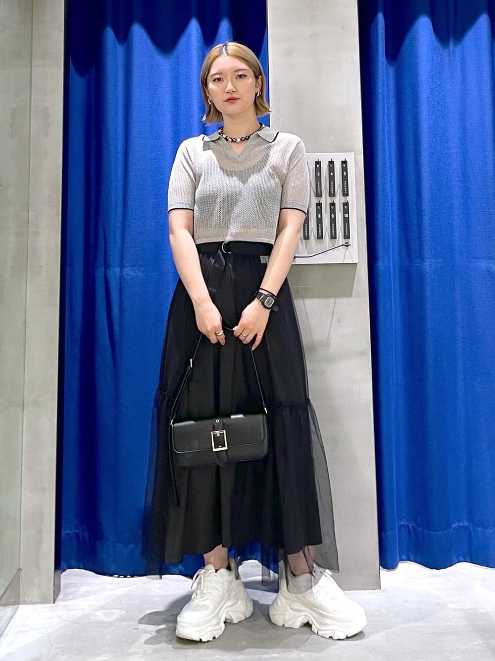 ホワイト系のスニーカー、ブラック系のハンドバッグ、ブラック系のニット/セーターを着用したレディースの夏コーディネートの4枚目の写真
